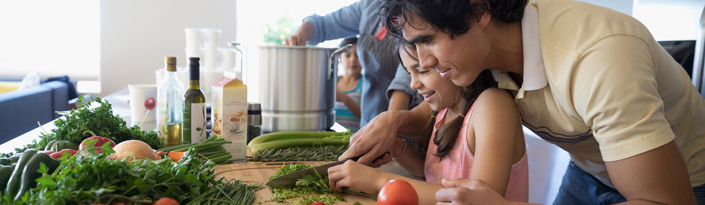 A father and daughter are chopping vegetables together in the kitchen 