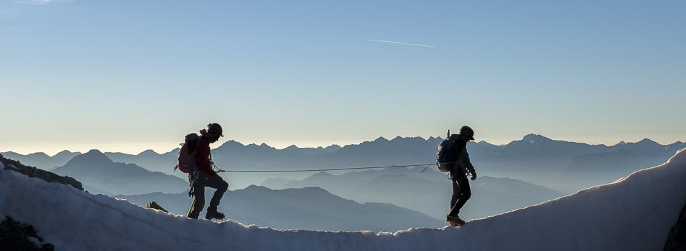 Trust Centre - security Two men walking on a mountain tethered by a security line