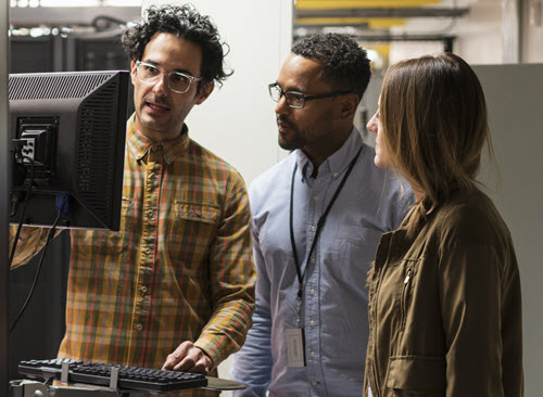 Work colleagues standing at a computer station